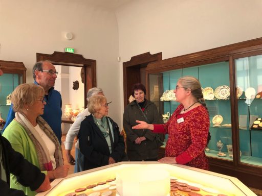 Besuchergruppe hört einer Museumsführerin in einem Ausstellungsraum zu.